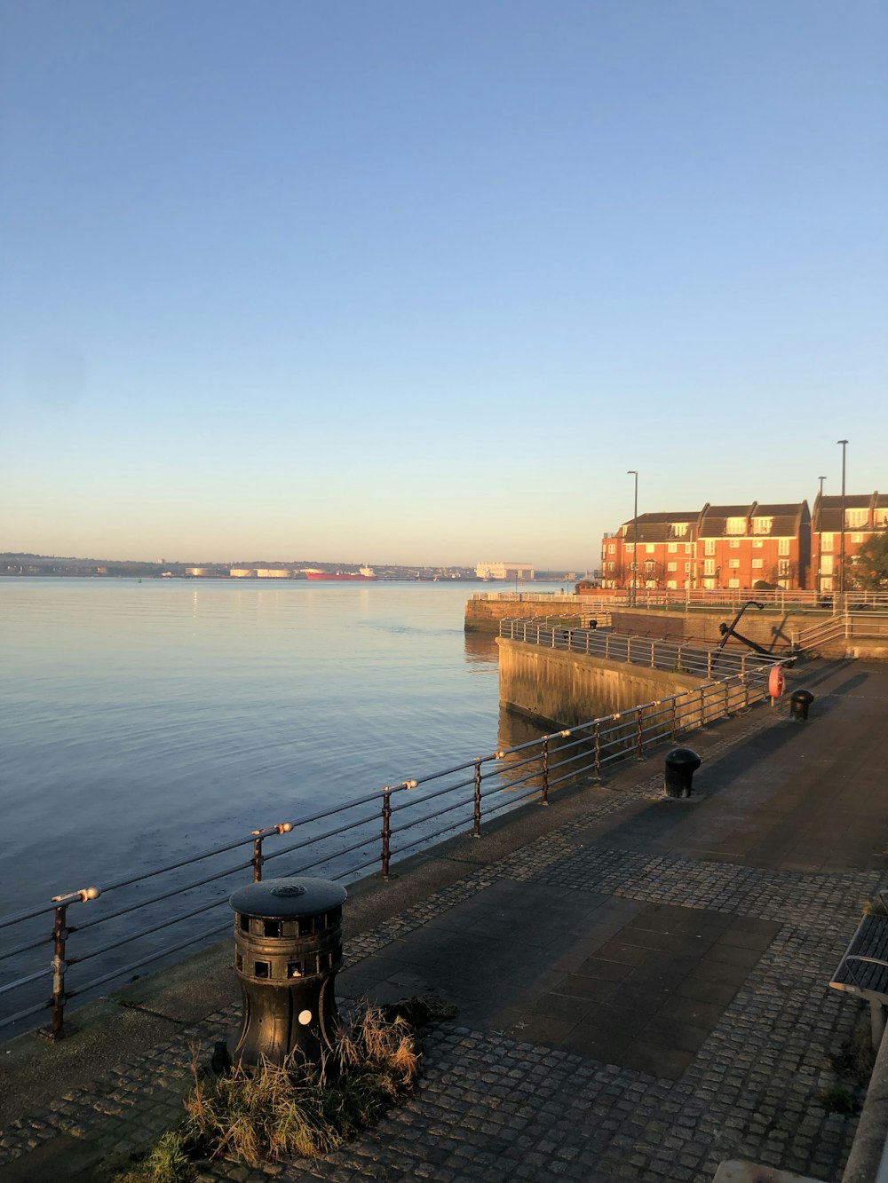 a large body of water next to a brick sidewalk