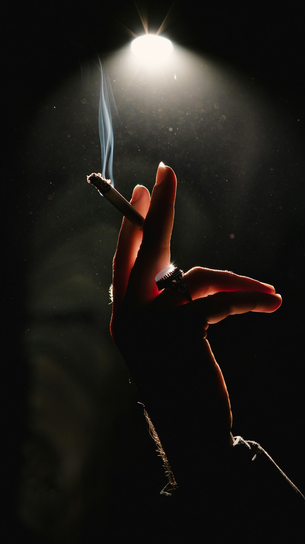 a person holding a lit cigarette in their hand