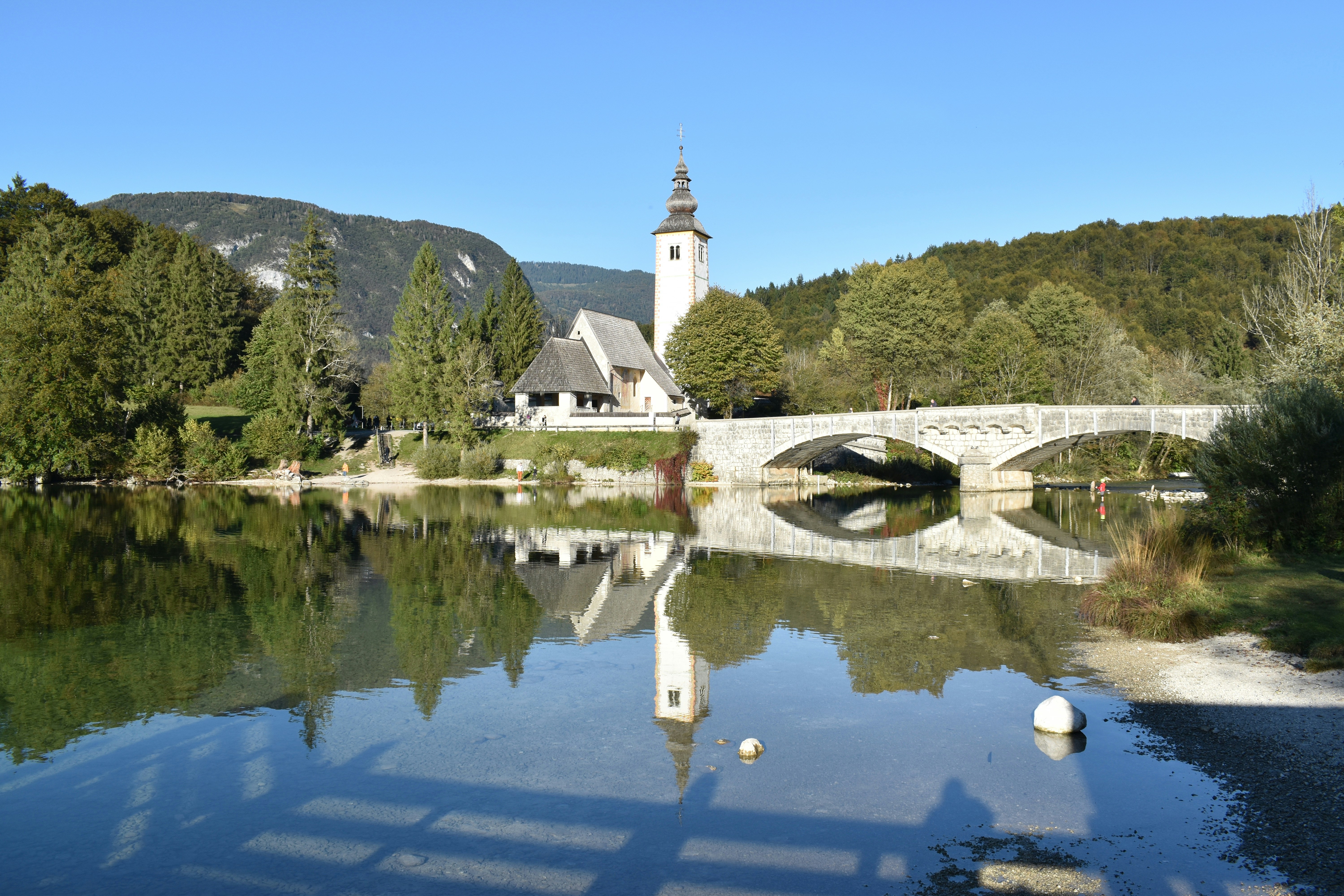a bridge over a river with a church in the background