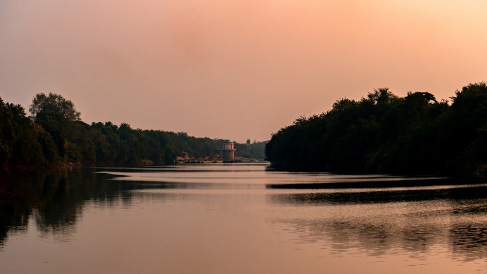 a body of water surrounded by trees under a cloudy sky