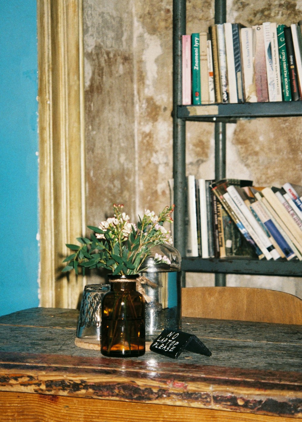 a vase of flowers on a table in front of a bookshelf