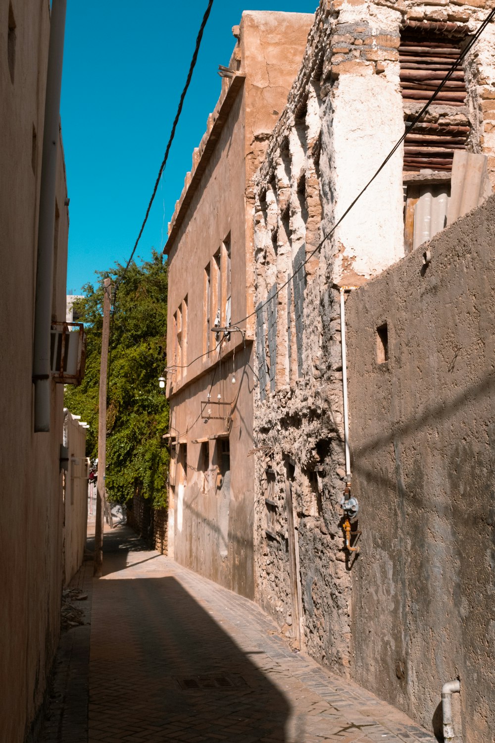 a narrow street with a stone building on the side