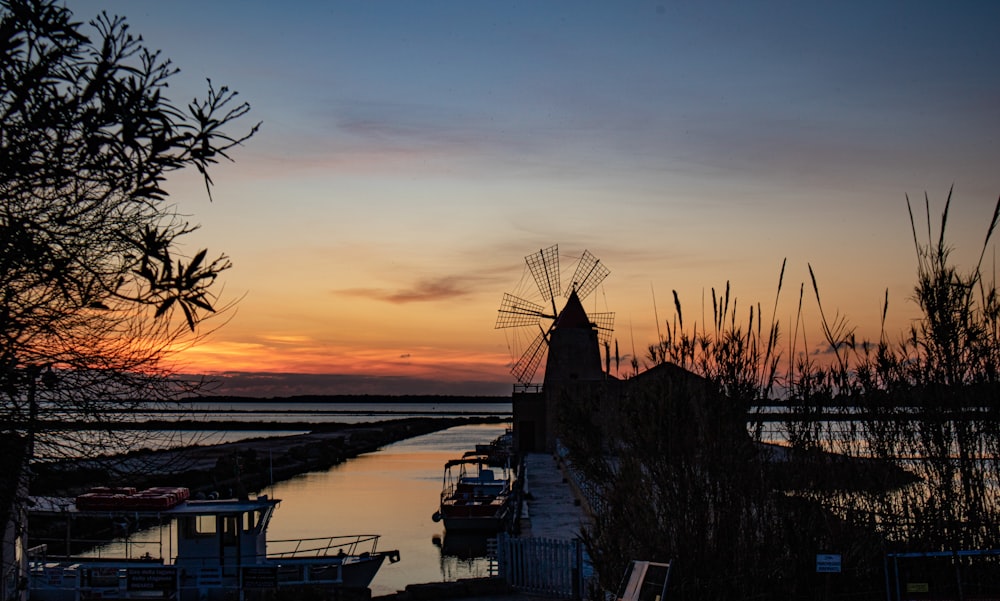 the sun is setting over the water and boats are docked