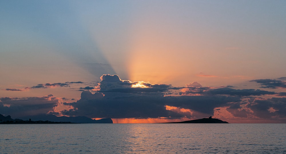 the sun shining through the clouds over a body of water