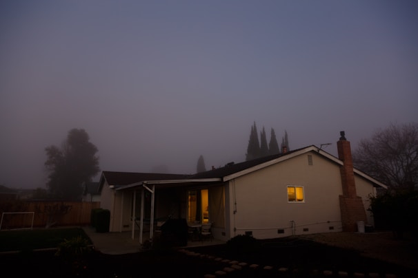 The eerie Elm Street house under a moonlit sky, wrapped in mist and darkness.