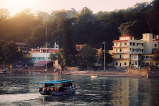 a boat traveling down a river next to a lush green hillside