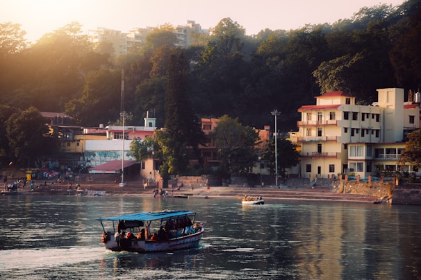a boat traveling down a river next to a lush green hillside