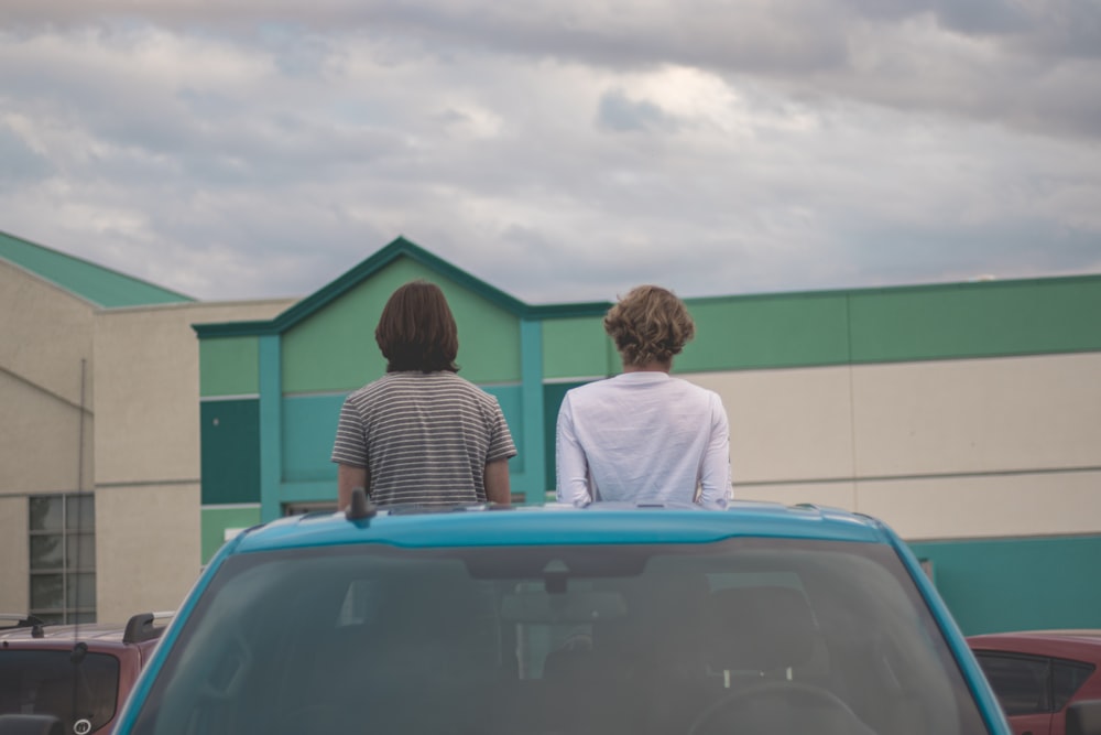two people sitting on the roof of a car