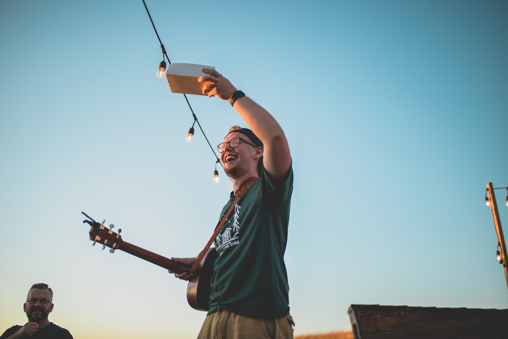 a man holding a guitar up to the sky