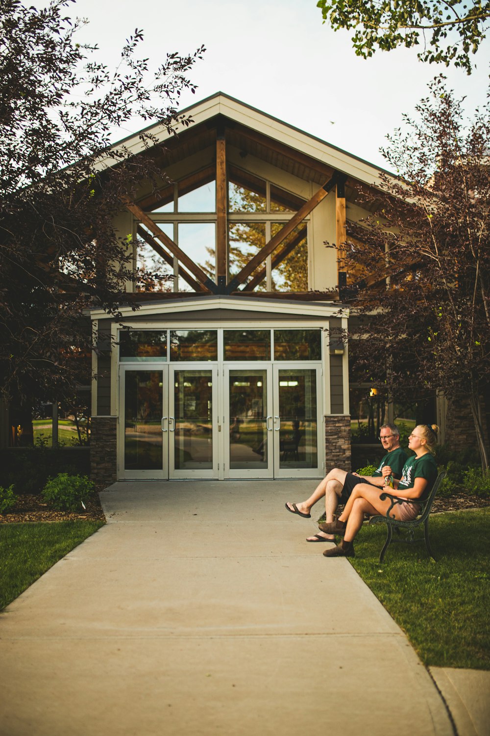 two people sitting on a bench in front of a building