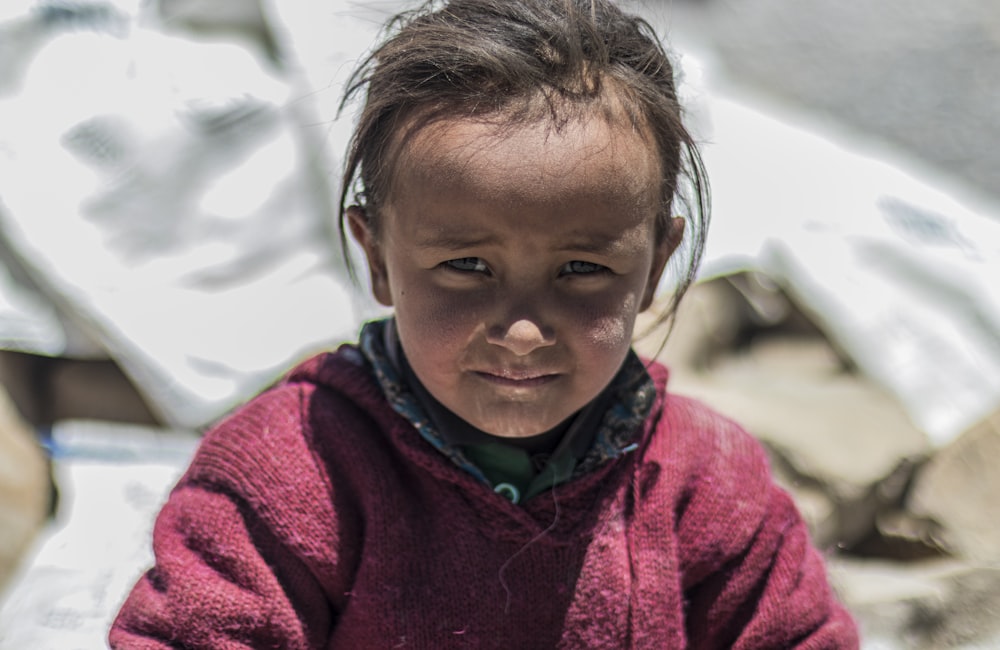 a little girl sitting on the ground with a piece of food in her hand