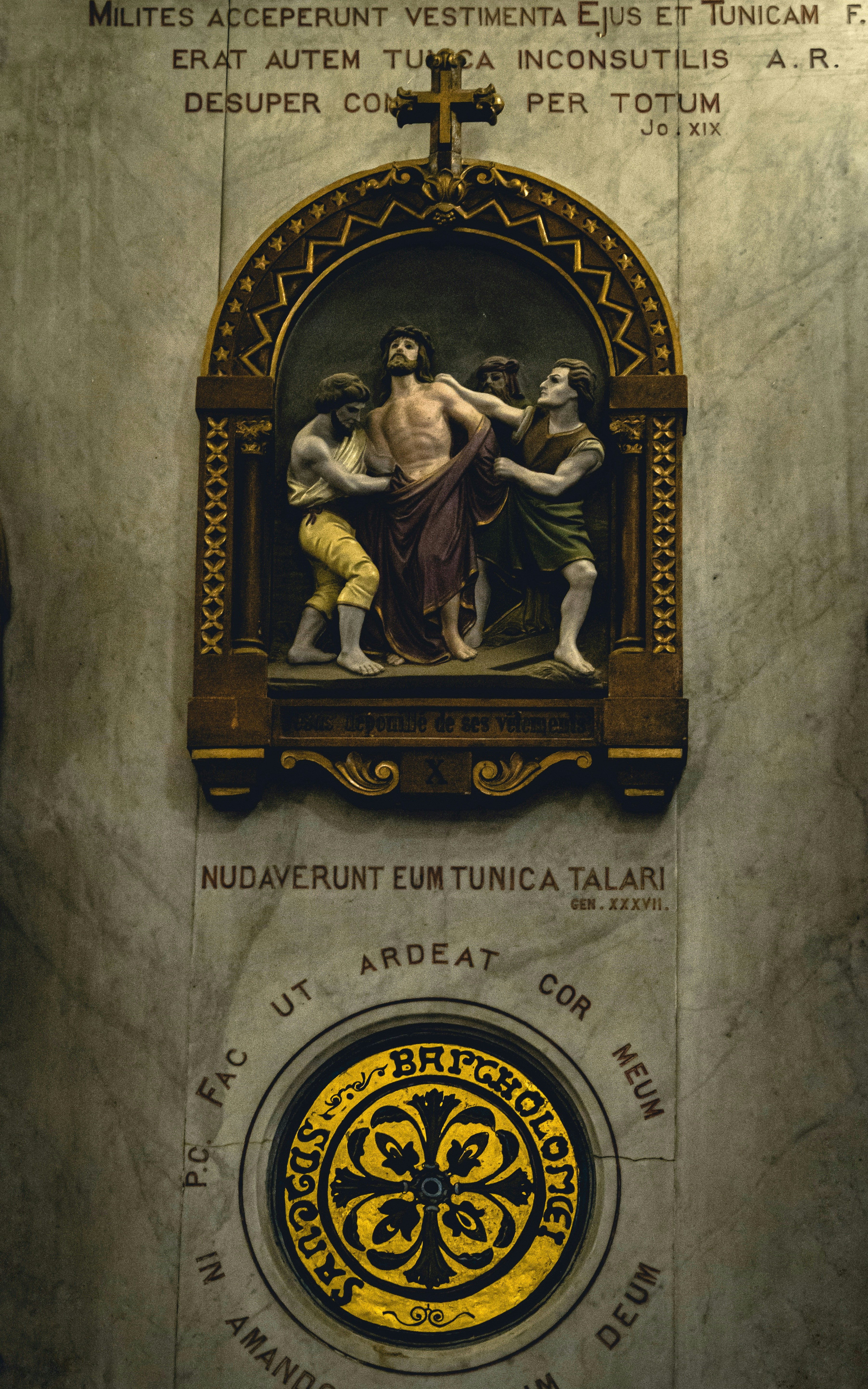 a statue of a man holding a cross on a wall