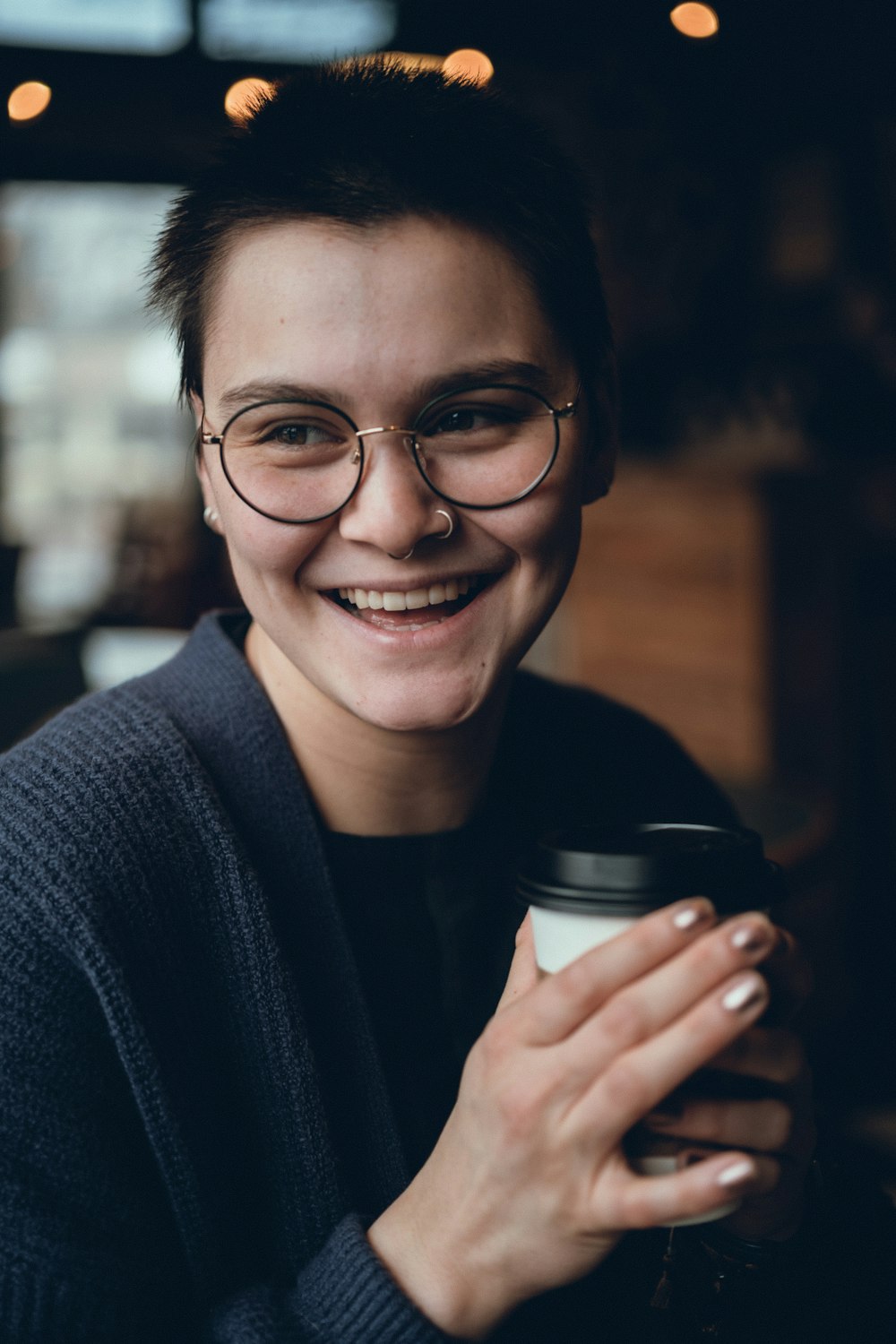 a smiling woman holding a cup of coffee
