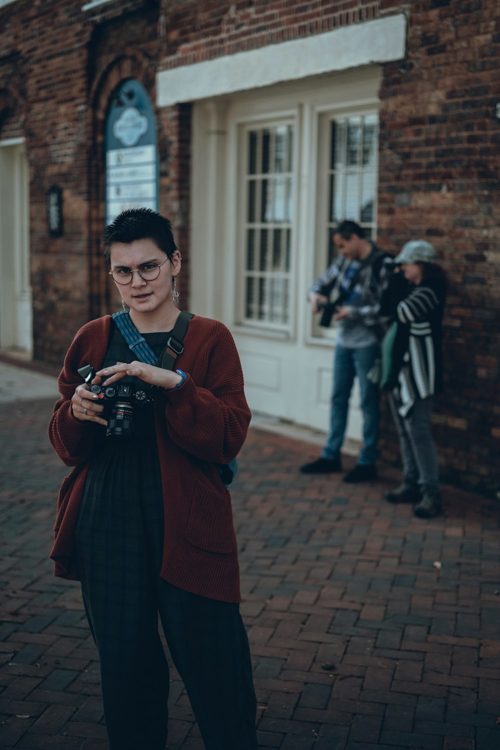 a woman standing in front of a brick building holding a camera