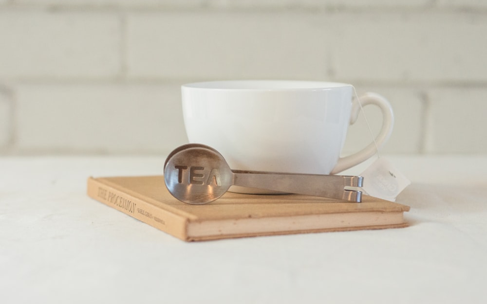 a white coffee cup sitting on top of a book