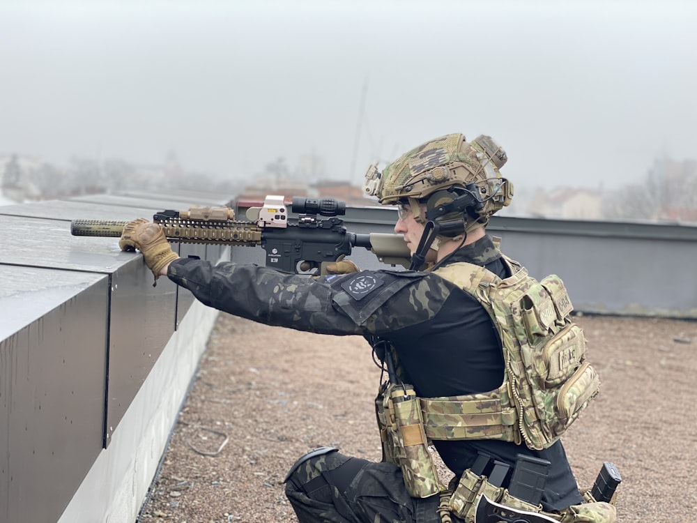 a man in camouflage holding a rifle and aiming it