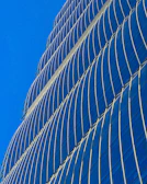 A luxurious commercial skyscraper with reflective glass facade under a clear sky.
