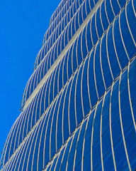 A sleek commercial office tower gleaming against a clear blue sky.