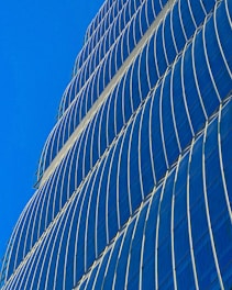 A sleek, glass-fronted office tower reflecting the Dubai skyline under a bright blue sky.