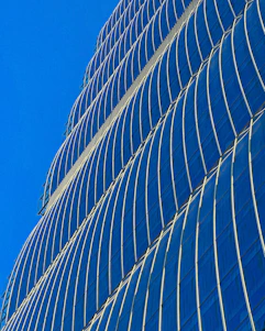 A sleek modern glass facade reflecting Dubai’s skyline under a clear blue sky.