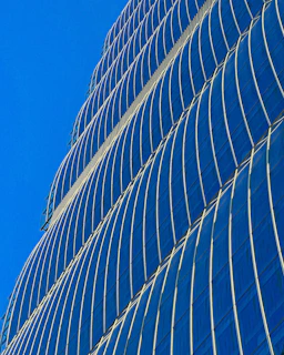 A sleek modern skyscraper gleaming under a clear blue sky.