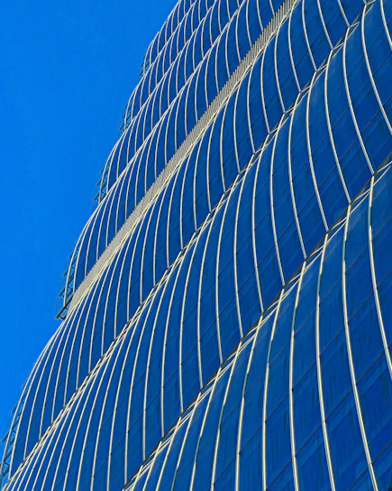 A sleek modern glass facade reflecting Dubai’s skyline under a clear blue sky.