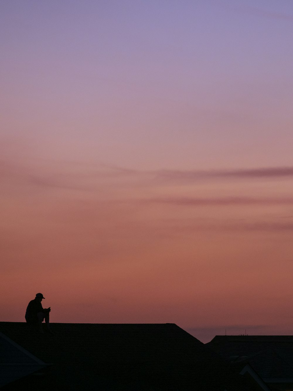 a man sitting on top of a roof next to a kite