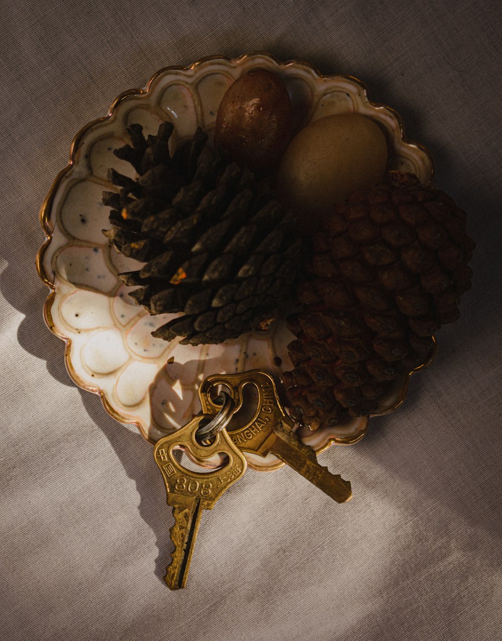 a plate with a key and a pine cone on it