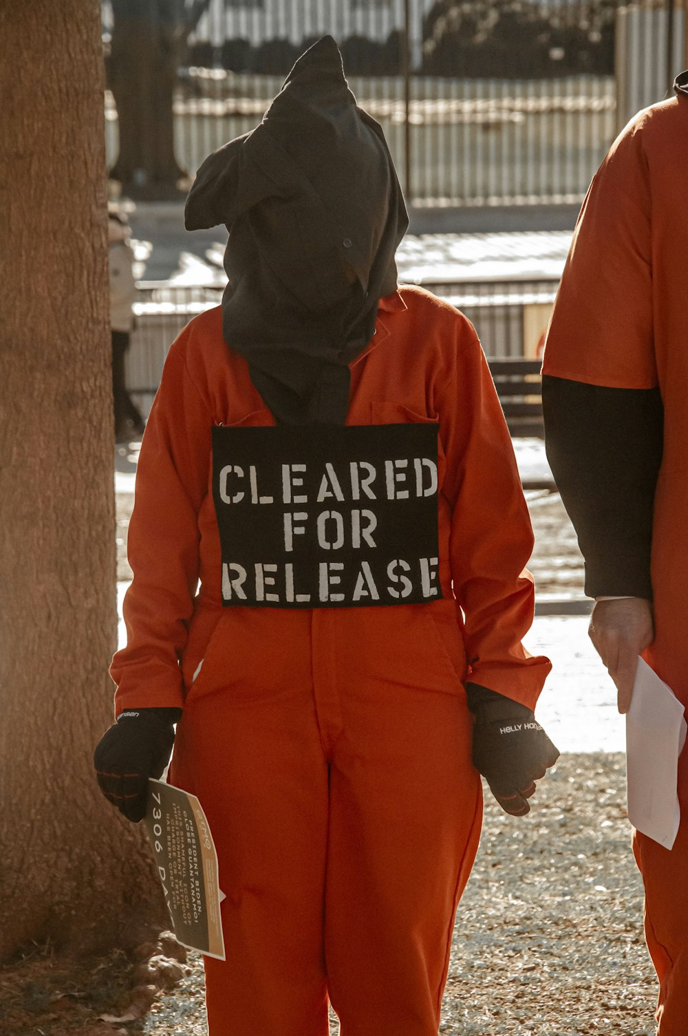 Deux personnes en combinaison orange avec une pancarte indiquant qu’elles ont été autorisées à être libérées