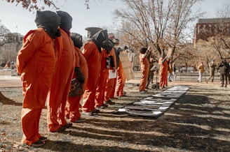 a group of people in orange jumpsuits standing in a line