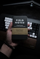 a person holding a book in front of a keyboard