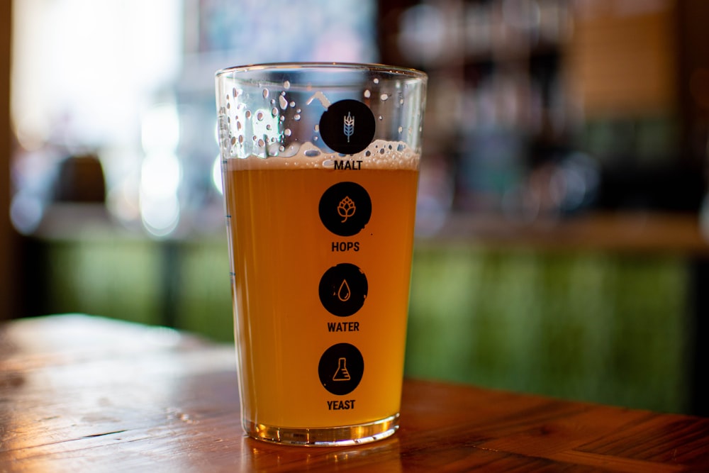 a glass of beer sitting on top of a wooden table