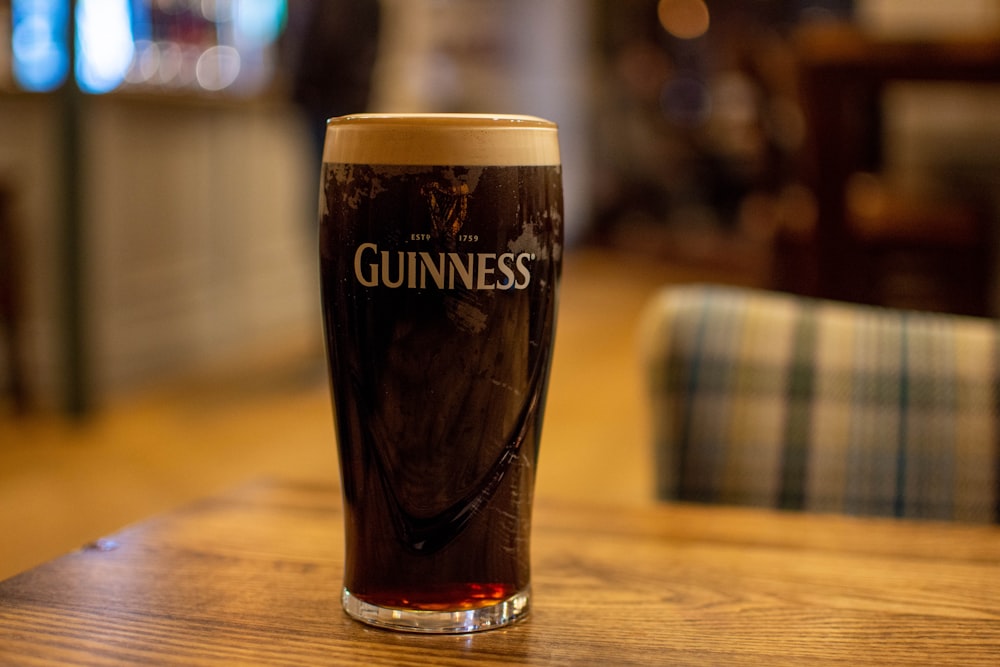 a glass of guinness sitting on a wooden table