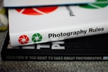 Stack of photography books with detailed images and explanatory charts on a wooden table