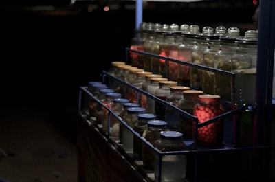 Jars of marinated fish arranged neatly on a shelf with warm lighting.