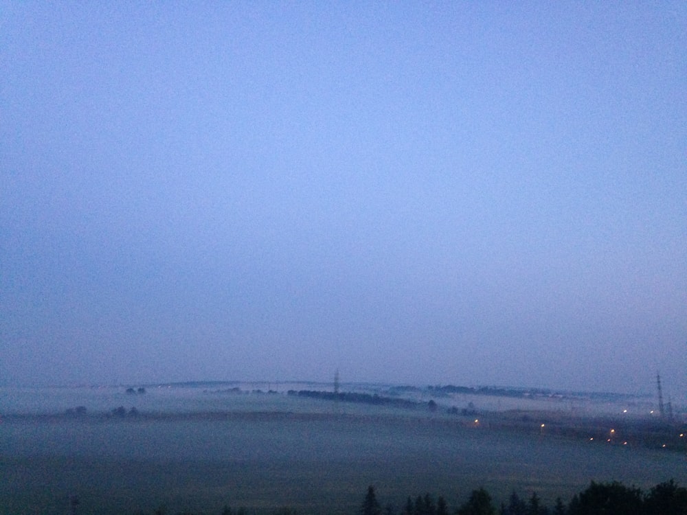 a foggy landscape with a bridge in the distance