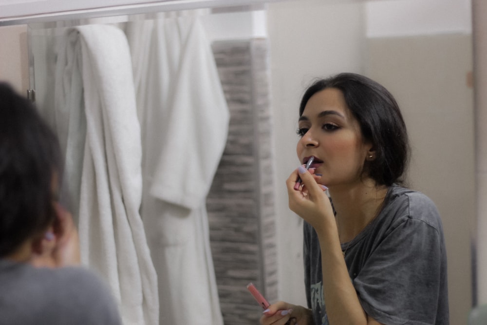 uma mulher escovando os dentes na frente de um espelho