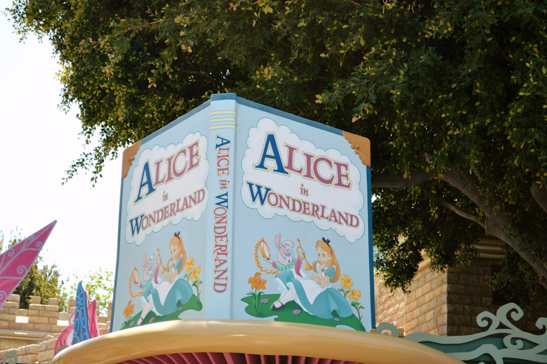 a sign for alice and the wonderland land in front of a tree,