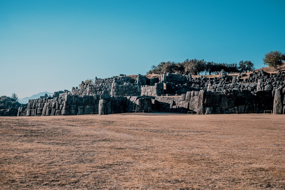 a large rock formation in a field with trees in the background