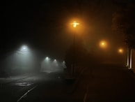 A foggy cobblestone street at night, illuminated by a single gas lamp.