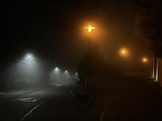 A foggy cobblestone street at night, illuminated by a single gas lamp.