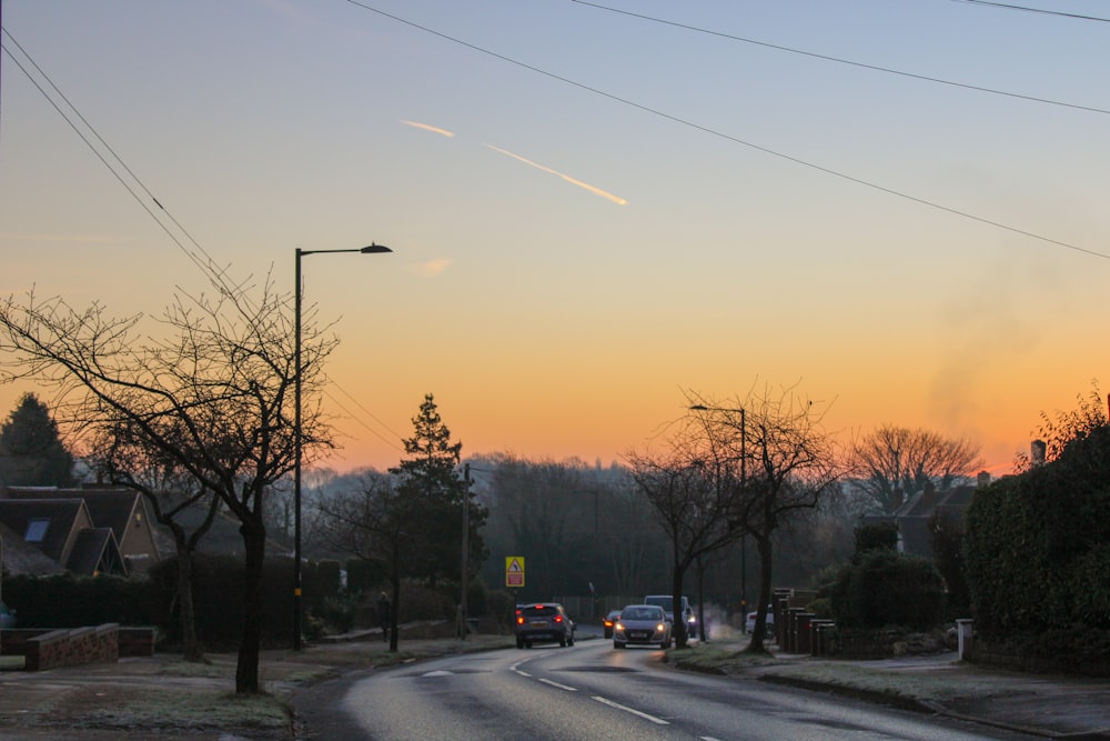 a street with cars driving down it at sunset