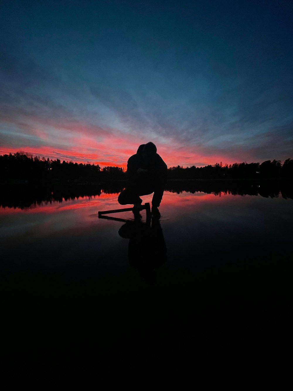 a person kneeling down in front of a body of water