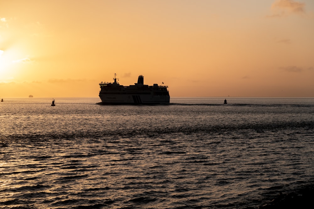 a large boat in the ocean at sunset