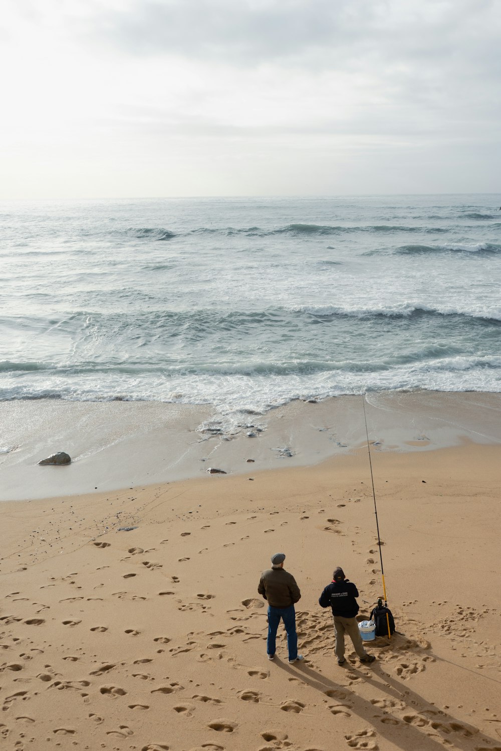 a couple of men standing on top of a sandy beach