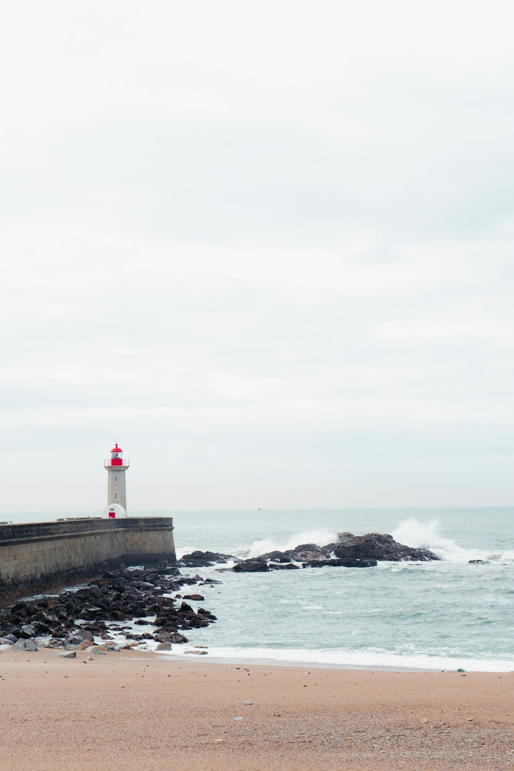 a light house on a rocky beach next to the ocean