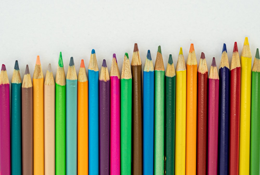 a row of colored pencils lined up against a white background
