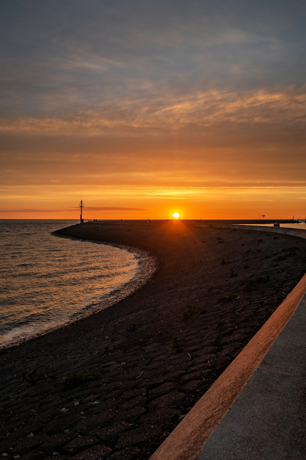 the sun is setting over the water at the beach