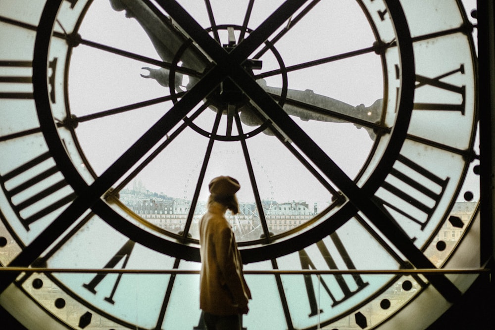 a person standing in front of a large clock