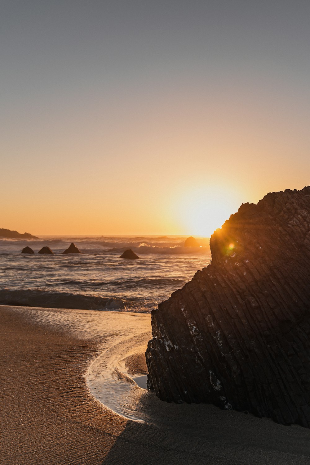 the sun is setting over the ocean on the beach